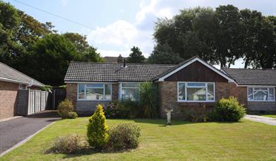 Exterior view of modern bungalow with green grass and blue sky