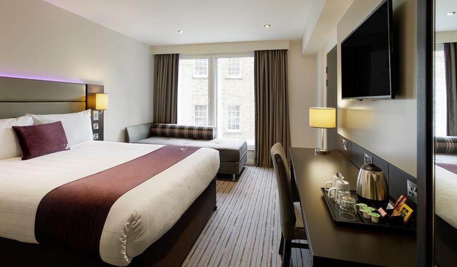 Interior of hotel room, with bed, desk, TV and window