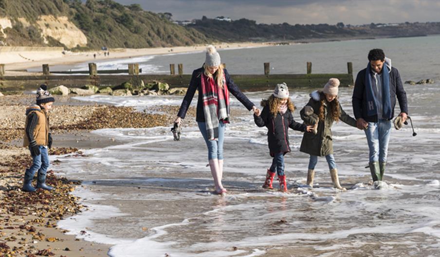 Family wrapped up warm whilst dipping their feet in the sea