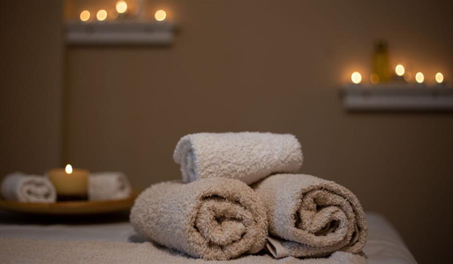 Towels rolled up on bench with soft candle light, interior scene