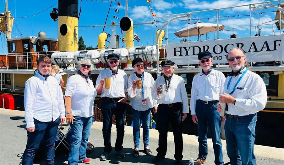 Group of singers in white shirts on the harbour side