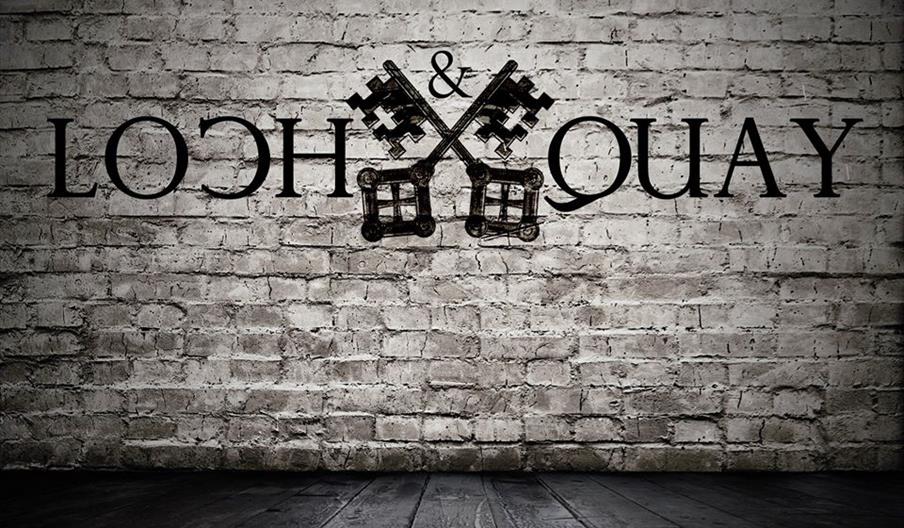 loch and quay logo superimposed on a white brick wall.