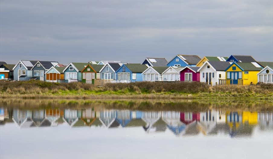 Colourful Mudeford beach huts in a row.