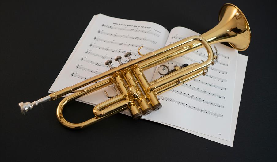 Trumpet on sheet music on black background
