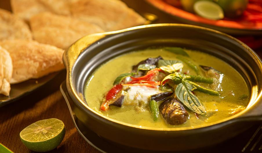 Thai dish in a bowl, with half a lime and crackers