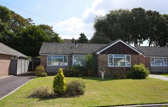 Exterior view of modern bungalow with green grass and blue sky
