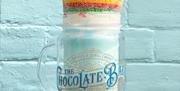 Bubblegum blast flavoured milkshake held against a blue brick wall