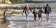 Family wrapped up warm whilst dipping their feet in the sea