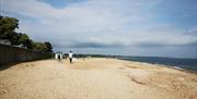 Wide shot of two people enjoying a walk out on the sand and shingle beach.