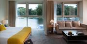 Junior suite at Captain’s Club Hotel overlooking the river, with a double bed, sofa and seating area